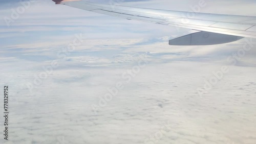 The view from the airplane window. Flying above the blue sky with moving clouds. Traveling on airplane at clear weather day.