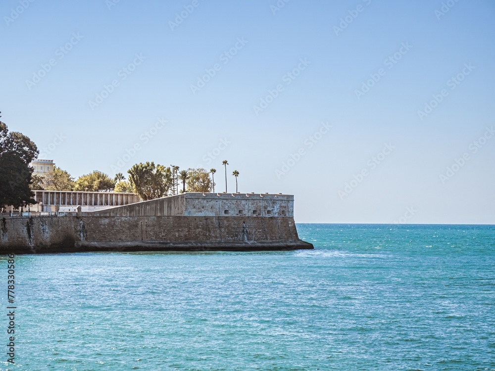 City walls with the bastion Baluarte de la Candelaria and the park of Alameda Apodaca in the Old Town of Cadiz, Spain