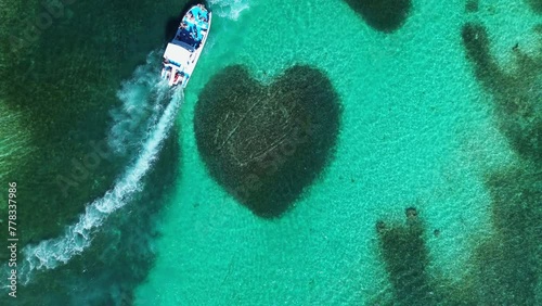 Aerial top view at Heart-shaped barrier reef coral. Turquoise ocean water. Tropical paradise. Catamaran boat with tourists. Caribbean Sea. Atlantic ocean. Zoom out.