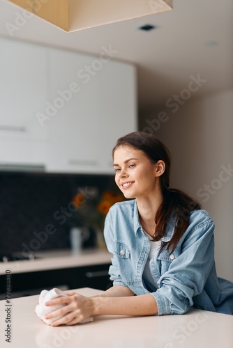 Woman cleaning apartment kitchen with rag in hand, indoor hygiene, home life with a smile
