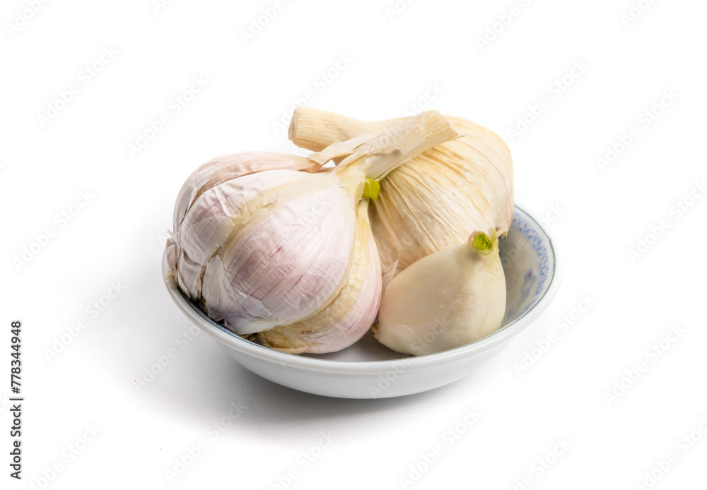 A small dish filled with cloves of garlic isolated on white A small dish filled with cloves of garlic isolated on white
