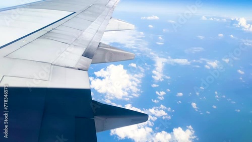 Time lapse The view from the airplane window. Flying above the blue sky with moving clouds. Traveling on airplane at clear weather day.