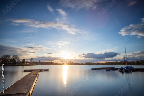 View from the shore into the distance and a sunset at the lake. The surroundings and the beautiful sky are reflected in the water. A great landscape shot Dutenhofener See, Hesse Germany
