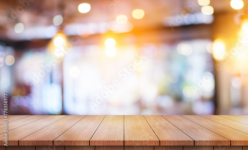 Empty wooden table top with lights bokeh on blur restaurant background © DEEP PIXEL