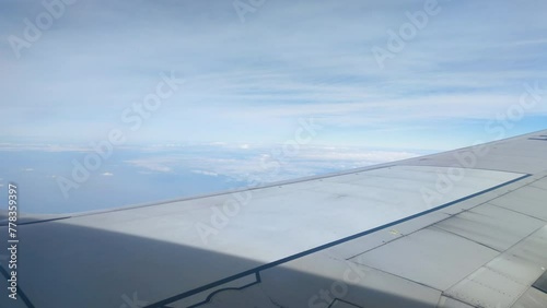 The view from the airplane window. Flying above the blue sky with moving clouds. Traveling on airplane at clear weather day.