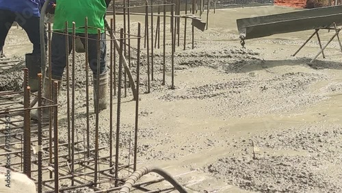 Workers pouring concrete floor Using a cement grinder to remove air bubbles and using a shovel to smooth out the cement.