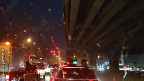 Cars parked at a red light while rain falls on the roads of Thailand.