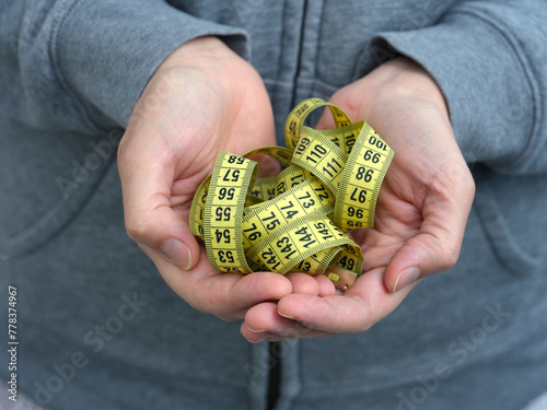 A woman holding a yellow tape measure in her hands. Close up.