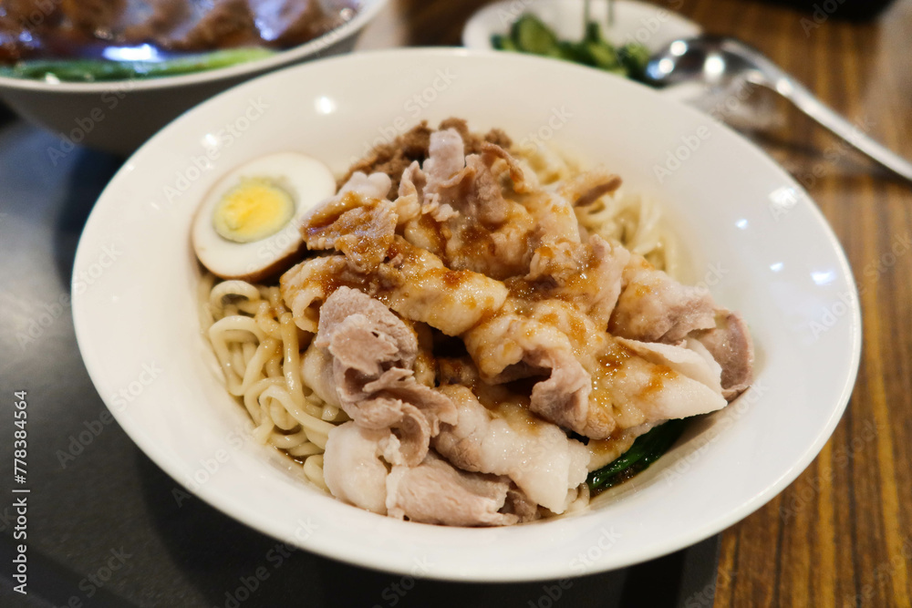 Chinese Taiwanese style boiled egg port soy sauce dry stirred noodles in a white plate Chinese Taiwanese style boiled egg port soy sauce dry stirred noodles in a white plate