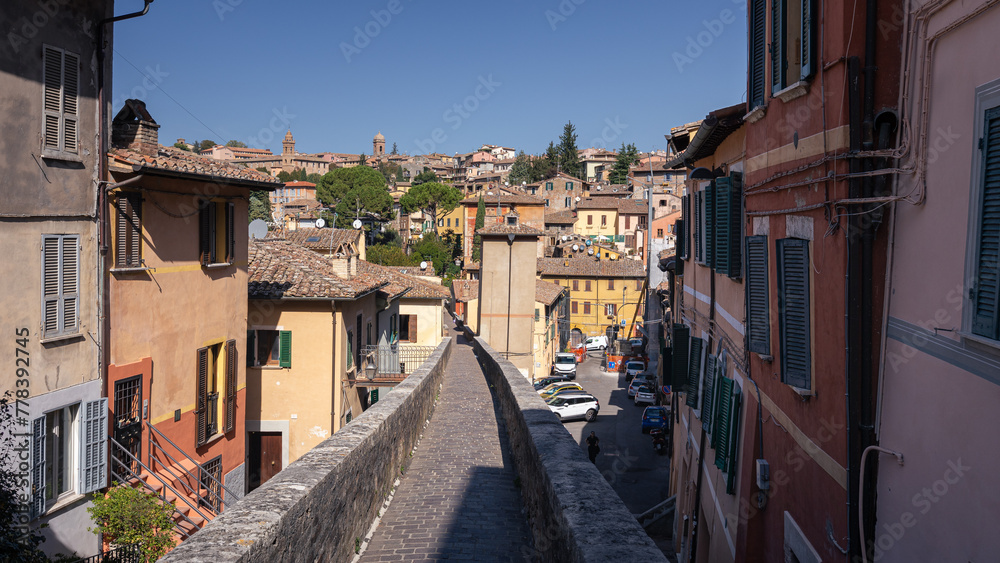 Narrow pedestrian street between old brick houses in ancient Italian city on sunny day, Perugia, Italy