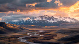 An epic, sweeping landscape view of the rugged Rocky Mountains at sunrise, with dramatic clouds pierced by golden rays, snow-capped peaks, and a winding river in the foreground 