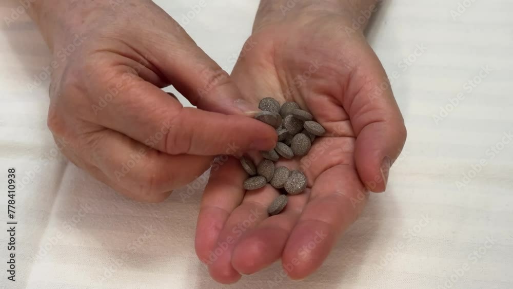 Close-up of the hand of an unknown elderly woman who chooses and puts different pills on her palm in background white color Close-up of the hand of an unknown elderly woman who chooses and puts different pills on her palm in background white color