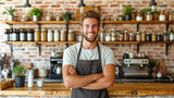 Cheerful young man with a beard wearing an apron in a modern coffee shop