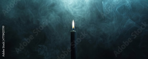 black candle on a dark background with fog. photo