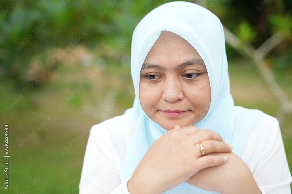 Portrait of an Asian female model wearing a blue hijab with various attractive facial expressions while out in nature during the day Portrait of an Asian female model wearing a blue hijab with various attractive facial expressions while out in nature during the day