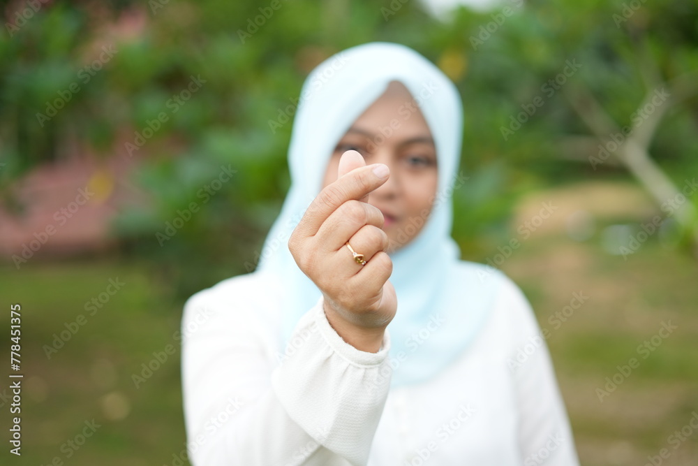 Portrait of Asian female model wearing blue hijab making love symbol with fingers Portrait of Asian female model wearing blue hijab making love symbol with fingers