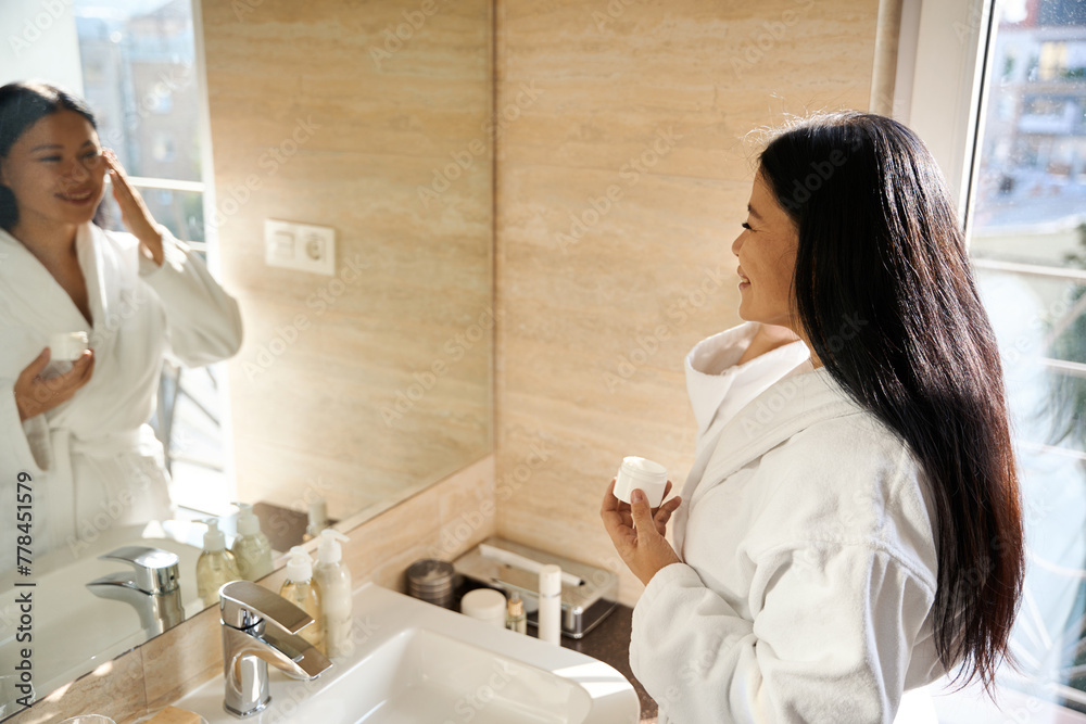 Smiling woman is using her cosmetic cream in bathroom Smiling woman is using her cosmetic cream in bathroom