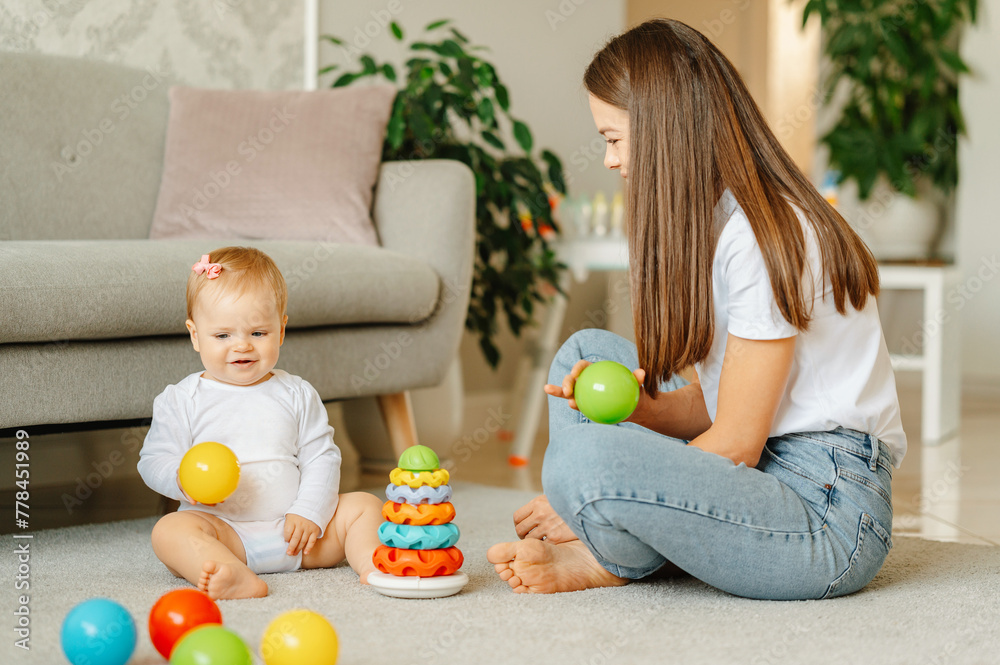 Indoor shot of a young mother playing together with her sweet smiling daughter. Indoor shot of a young mother playing together with her sweet smiling daughter.