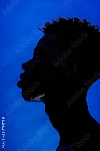 Side view profile outline of African-American male silhouette against deep blue background