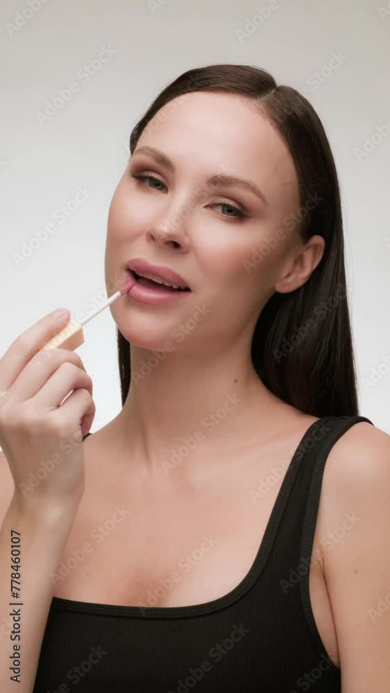 Beautiful brunette woman with clean skin applies lip gloss. Daily beauty routine Beautiful brunette woman with clean skin applies lip gloss. Daily beauty routine