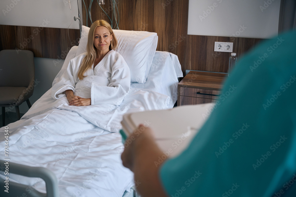 Pleased female patient being served meal in medical facility ward - obrazy, fototapety, plakaty 
