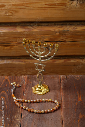 Menorah and rosary on a wooden table on a wooden wall photo