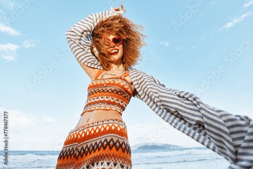 Summer Beach Vacation: Smiling Woman Embracing Freedom and Joy in Nature, Close-up of Curly-haired Beauty with Freckles, Enjoying the Sunlight and Happiness with Headphones, Outdoors on a Colorful