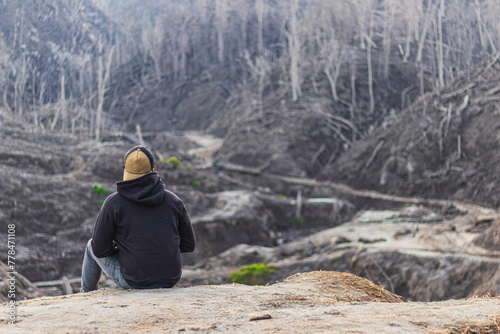 фотографія landscape of a lonely man sitting on the slopes of volcano