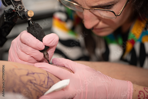 Close-up of woman tattooing a client's arm