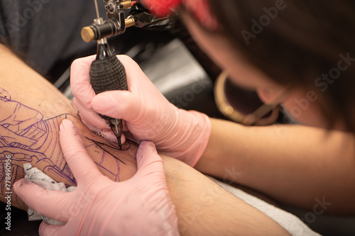 Close-up of woman tattooing a client's arm