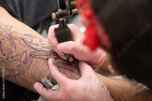 Close-up of woman tattooing a client s arm