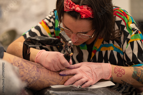 Tattoo artist woman performing a tattoo on an arm