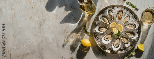 A high angle, wide landscape right justified photo of beautifully prepared raw oysters on the half shell, served on ice with white wine and Lemons  photo