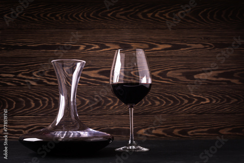 Decanter and glass with red wine on wooden rustic background photo