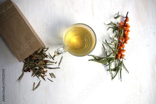 sea buckthorn leaves and berries tea in cup on wooden background