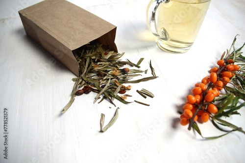 sea buckthorn leaves and berries tea drink in cup on wooden background