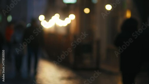 Rainy City Blur: A defocused glimpse into the wet nocturnal streets, where lights shimmer and figures move in a dance of urban life. photo