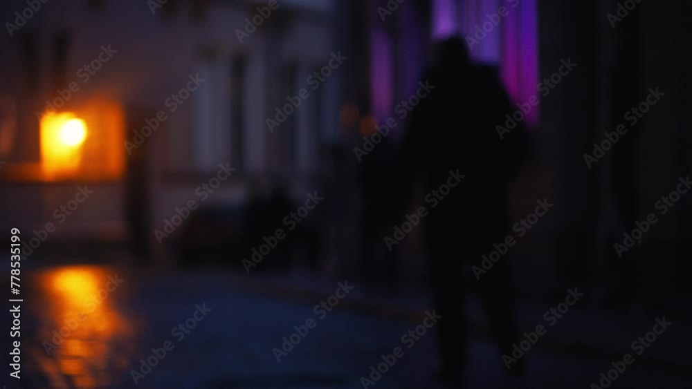 Rainy cityscape: In this defocused scene, the city comes alive at night amidst wet weather, with blurred silhouettes of pedestrians moving through illuminated streets. Rainy cityscape: In this defocused scene, the city comes alive at night amidst wet weather, with blurred silhouettes of pedestrians moving through illuminated streets.