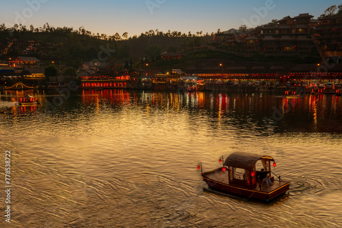 Rak Thai Village at night, lights from tour boats reflect on the water. Yunnan Chinese village style It is a famous tourist attraction and a landmark of Mae Hong Son Province. Northern Thailand. photo