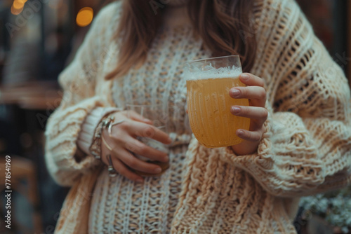 Close-up photo of an unrecognizable pregnant woman enjoying a non-alcoholic beverage at a social event