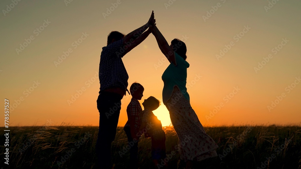 Happy family dreams of their own home. Kids. Family home symbol for child mom dad. Taking care of children by parents. Children mom dad are playing building house with their hands, silhouette, sunset.