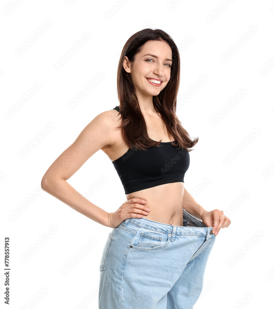 Happy young woman in big jeans showing her slim body on white background - obrazy, fototapety, plakaty 