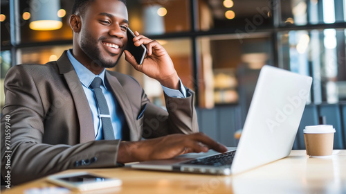 Title: "Businessman at Work"Art Description: A businessman in business attire, smiling and working on his laptop while talking on the phone in a modern office setting. 