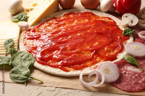 Pizza base smeared with tomato sauce and products on light textured table, closeup © New Africa