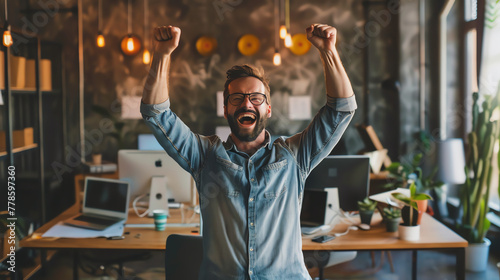 A young professional entrepreneur celebrating success in a startup office, raising arms with a triumphant expression, surrounded by modern workspace.