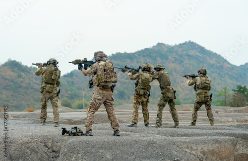 Side view group of military or soldiers stand with point gun to left side to the enemy in area of battlefiled or practice area.