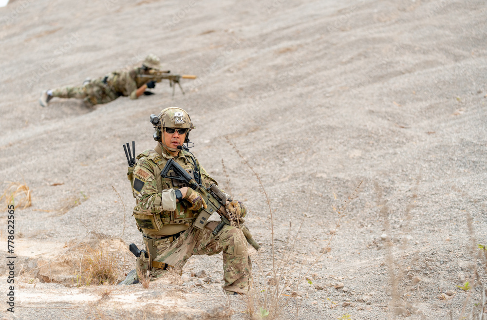 One of military or soldier sit with hold the gun and look at camera while the other lie down on the ground during outdoor practice. One of military or soldier sit with hold the gun and look at camera while the other lie down on the ground during outdoor practice.