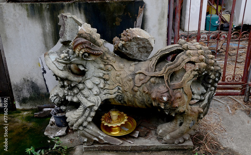Closeup of Old stucco doll (carved marble pixiu) broken with the golden tray is located inside a Thai Buddhist temple at Thailand.