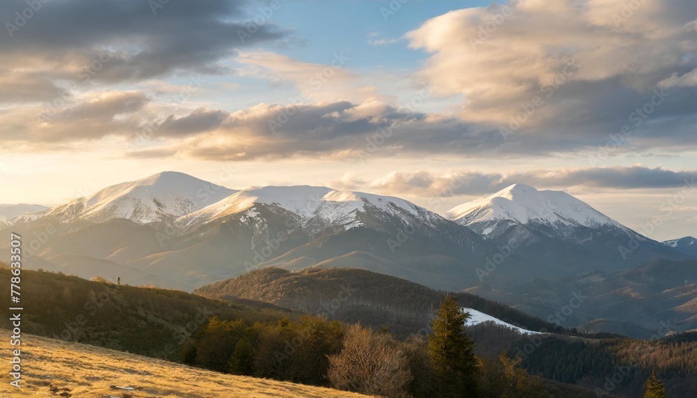 carpathian mountains nature background in spring landscape with snow capped tops of borzhava in morning light beneath a sky with clouds