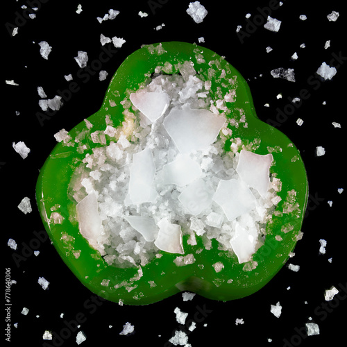 Composition of a sweet pepper and salt contrasting against black background, seen from above